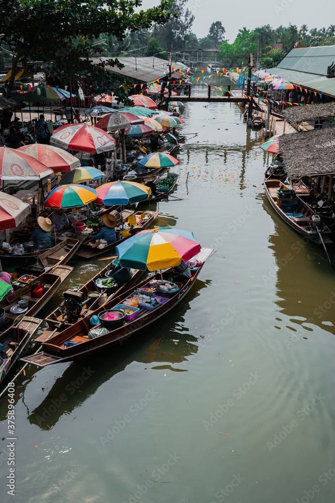Calm hour in one of Thailands floating market, boats filled with delicacy and colorful umbrellas protecting them from the sun.