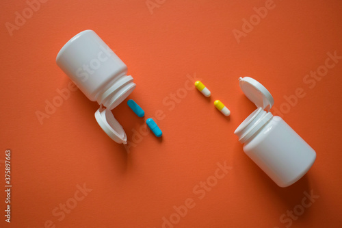Yellow-white and blue capsules with two open white packages on a brown background, top view.