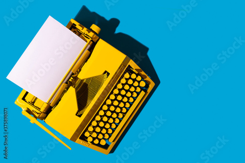 Yellow bright typewriter on blue. Symbol for writing, blogging, new ideas and creativity. Copy space photo