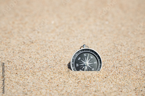  Close-up image of a compass on the sand. Copy space. Summer Travel destination and Navigation Concept.