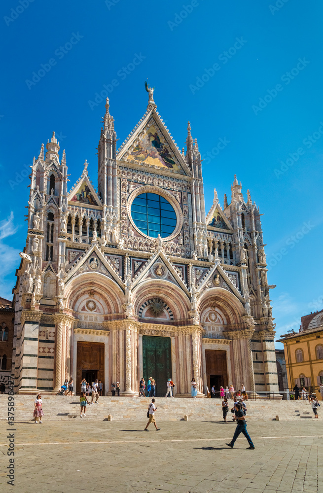 Lovely portrait shot of the impressive west façade of the historic Duomo di Siena, the famous medieval church in Siena, Italy. The cathedral is a masterpiece of Italian Romanesque–Gothic architecture.