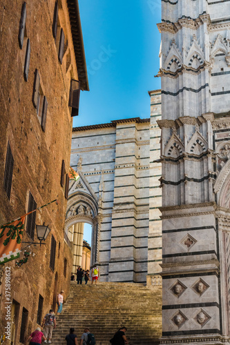 Nice view of a steep staircase leading to the side portal Porta laterale del Duomo Nuovo from Piazza San Giovanni; used as a passage between Piazza del Duomo and the street Via di Monna Agnese, Siena. photo