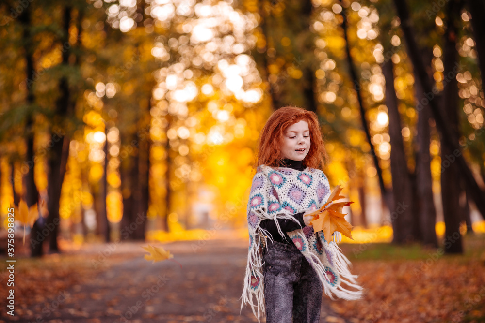 Beautiful red head girl holding autumn leaves and posing for camera, colorful photo Beautiful red head girl holding autumn leaves and posing for camera, colorful photo
