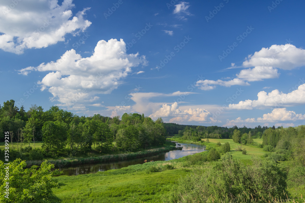 Beautiful landscape with view from the hill to Salaca river in Latvia on summer sunny day running among green meadows and forest. Beautiful blue sky with white clouds over it Beautiful landscape with view from the hill to Salaca river in Latvia on summer sunny day running among green meadows and forest. Beautiful blue sky with white clouds over it