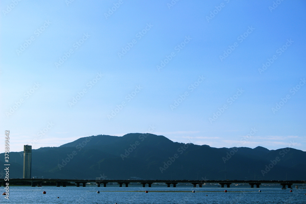 湖越しに見る夏空の下の山と橋