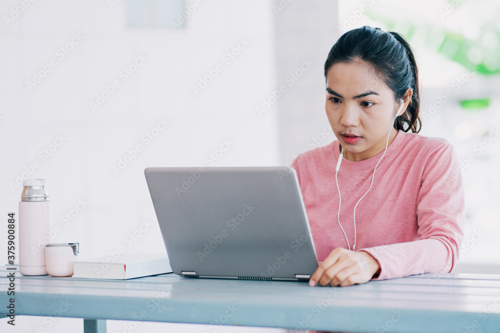 Young Asian freelance businesswoman working on a laptop at home during Coronavirus or COVID-19 pandemic. Young adult learner studying at home concept. Stock photo Young Asian freelance businesswoman working on a laptop at home during Coronavirus or COVID-19 pandemic. Young adult learner studying at home concept. Stock photo