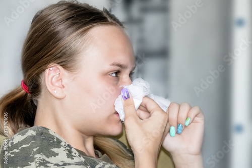 teenage girl caught a cold and wipes her nose with a tissue
