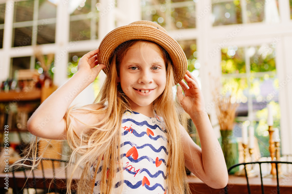 girl in a straw hat stand in vintage-style room.
