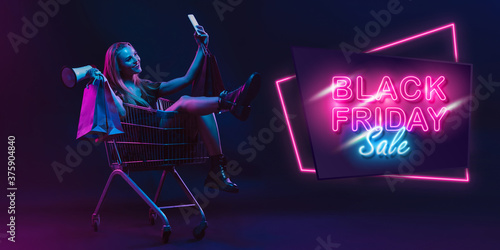 Selfie, megaphone. Portrait of young woman in neon on dark studio backgound. Human emotions, black friday, cyber monday, purchases, sales, finance concept. Copyspace. Seamless post for instagram.