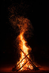 Camp fire in the night. Burning wood at night. Campfire at touristic camp at nature in dark. Flame amd fire sparks on black  background. Hellish fire element. Fuel, power and energy