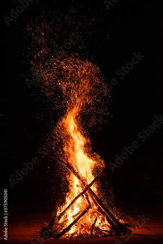 Camp fire in the night. Burning wood at night. Campfire at touristic camp at nature in dark. Flame amd fire sparks on black  background. Hellish fire element. Fuel, power and energy
