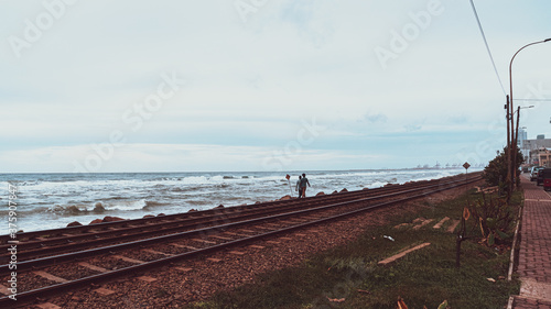 Tory kolejowe nad oceanem w pochmurny dzień.