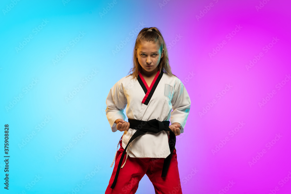Powerful. Karate, taekwondo girl with black belt isolated on gradient