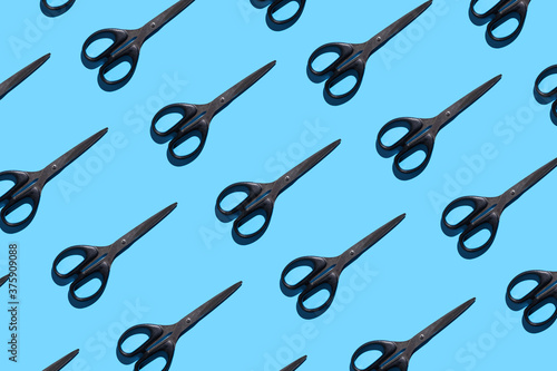 Open and closed black stationery scissors on a blue background. Pattern with stationery scissors. The concept of office supplies, school, student body, needlework.
