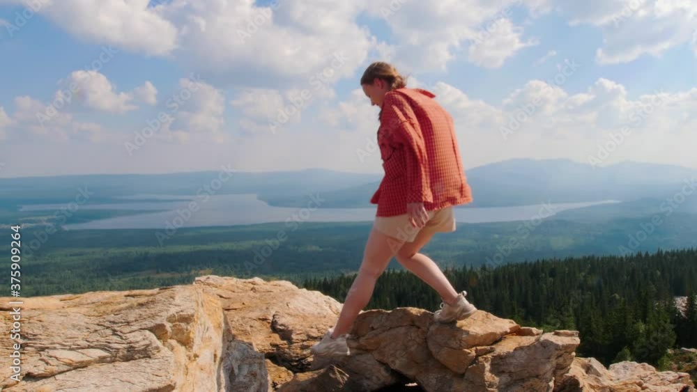 Young woman climbing on the mountain and raises her hands up Young woman climbing on the mountain and raises her hands up