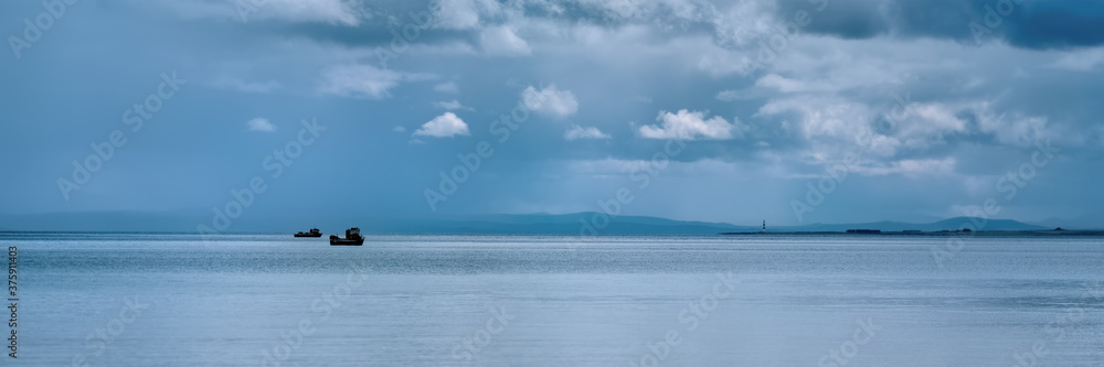 Fishing boats off Tarbatness lighthouse in the Highalnds with clouds and rain Fishing boats off Tarbatness lighthouse in the Highalnds with clouds and rain