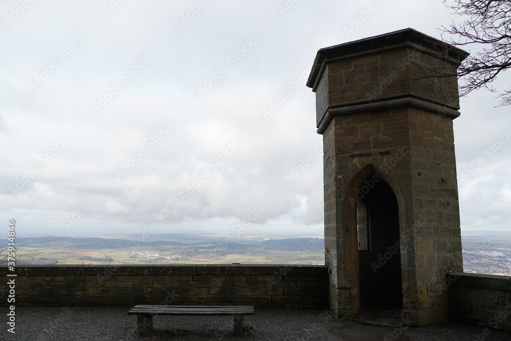 A small tower on the outer walls of the Hohenzollern castle in Germany, Europe. There is a view on the surrounding landscape and the overcast sky with low clouds. 