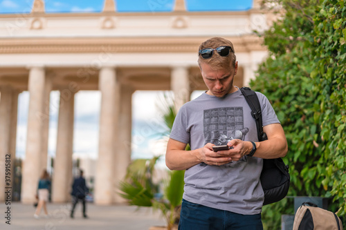 A young man stands in a Park and uses his mobile phone, Gorky Park