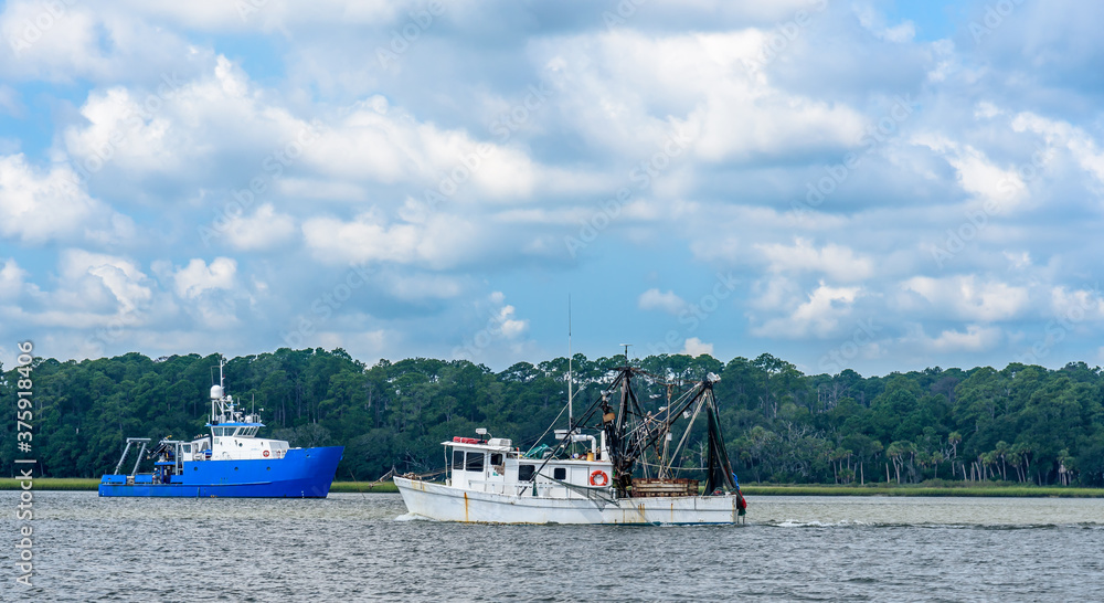 A Shrimp Boat Trawler Heading to Sea for a Day of Fishing  next to a Research Vessel in Savannah Georgia