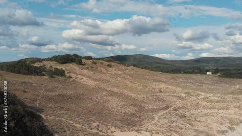 High sandy hill with green vegetation at the top. Shooting with a drone.