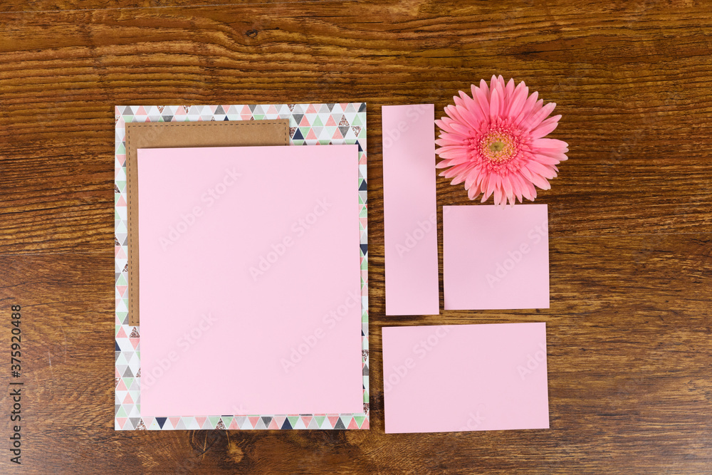 Pink sheet of papers surrounded by a flower on wood table Pink sheet of papers surrounded by a flower on wood table