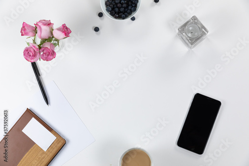 View of school supplies with flowers, phone and perfume on white background
