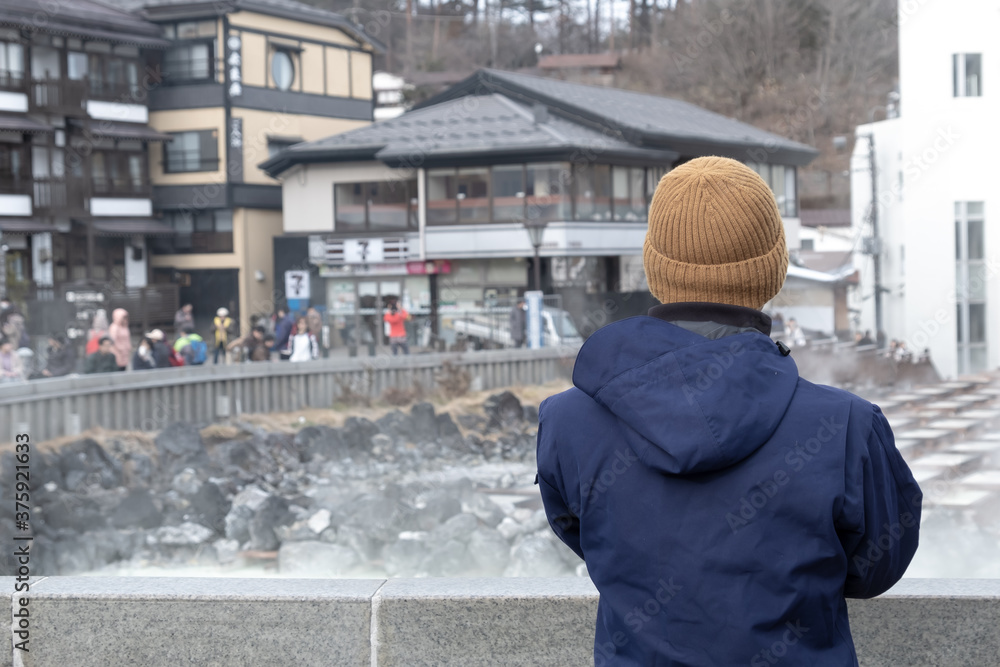 Back view of tourist traveler man sightseeing Hot springs at kusatsu onsen in winter japan Back view of tourist traveler man sightseeing Hot springs at kusatsu onsen in winter japan