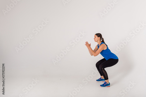 the sportswoman performs squats on a white background with space for text