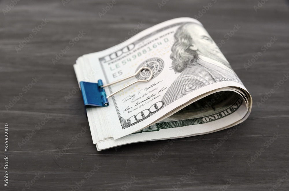 hundred dollar bills with a metal clip on a black wooden background. Financial concept. Close-up. hundred dollar bills with a metal clip on a black wooden background. Financial concept. Close-up.