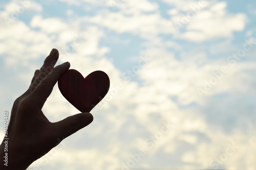 Valentine heart background with copy space. Hand holding a heart against blue sky