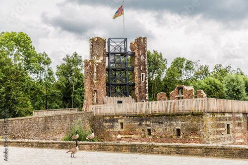 Tower with a flag of the Limburg province, remodeled brick walls of the Schaesberg castle with green trees in the background, cloudy day with a gray sky in Landgraaf South of Limburg, Netherlands photo