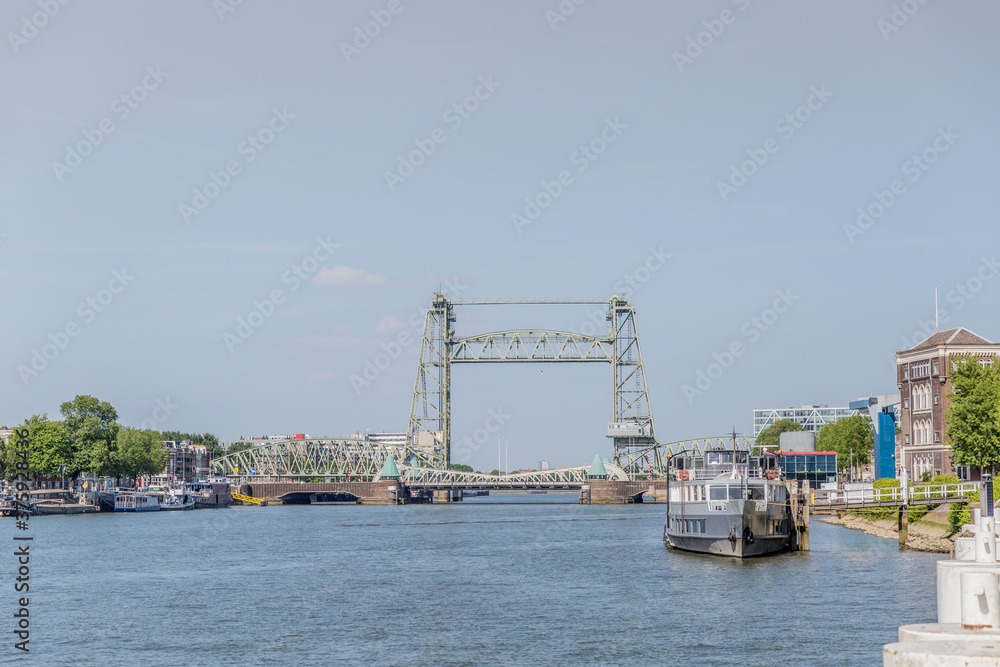 Boats anchored at the small docks with the Hef railway bridge or Koningshaven bridge in the background, sunny day with a blue sky in Rotterdam in the Netherlands Holland