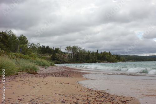 sandy beach in the afternoon light and wavy water