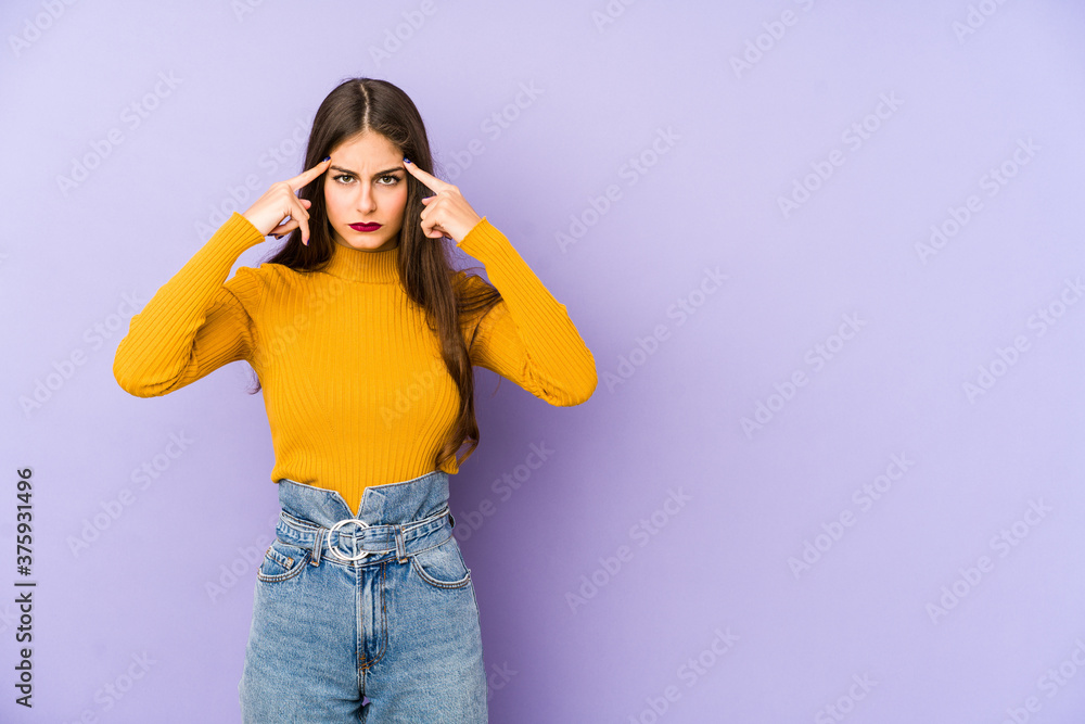 Young caucasian woman isolated on purple background focused on a task, keeping forefingers pointing head. Young caucasian woman isolated on purple background focused on a task, keeping forefingers pointing head.