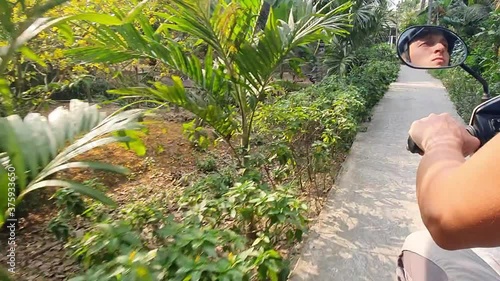 young man riding bike in Asia. male tourist travellig in Vietnam by bike. sunny landscape, road, scooter rent for tourists. vacation in Asia. photo