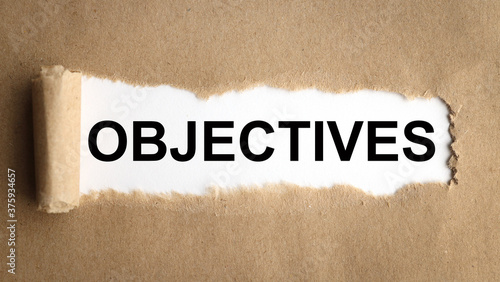 objectives. text on white paper on torn paper background.