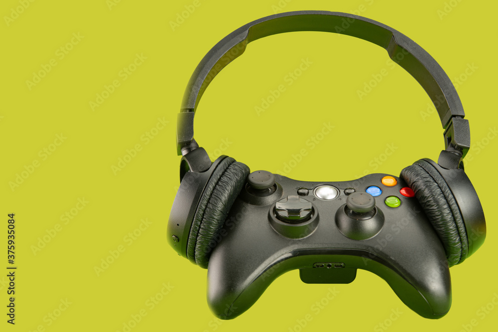Video game controller using a headset on a green background surface, selective focus. Video game controller using a headset on a green background surface, selective focus.