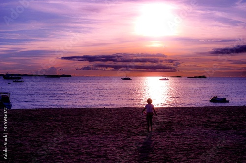 A child was playing in the evening on a beach in Thailand.