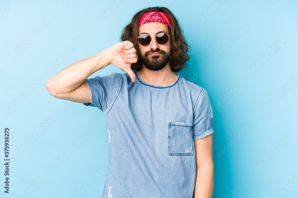 Young long hair man wearing a festival hipster look isolated showing a dislike gesture, thumbs down. Disagreement concept. Young long hair man wearing a festival hipster look isolated showing a dislike gesture, thumbs down. Disagreement concept.