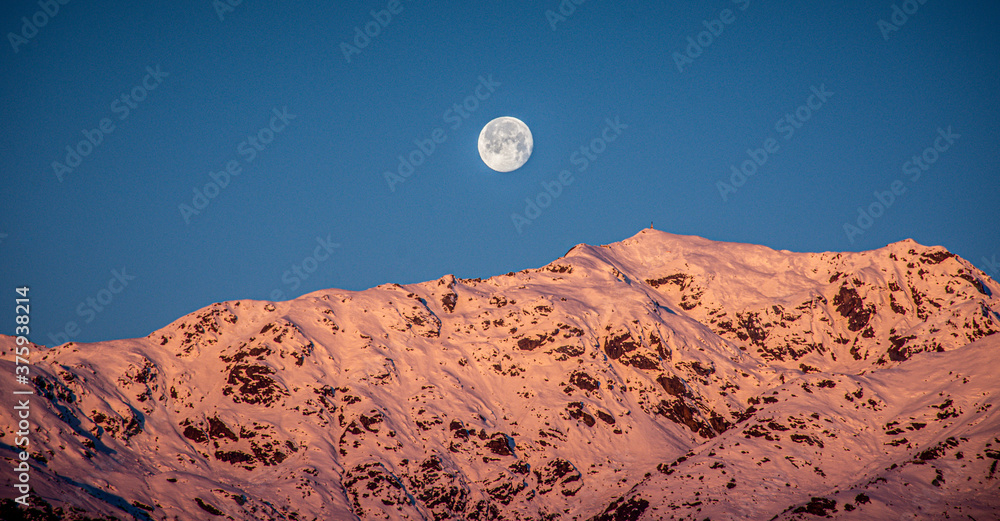 The moon sets behind the Alps