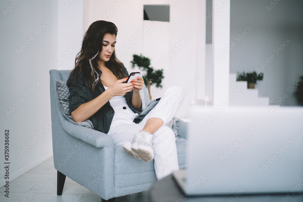Young brunette with long hair browsing mobile phone at home Young brunette with long hair browsing mobile phone at home