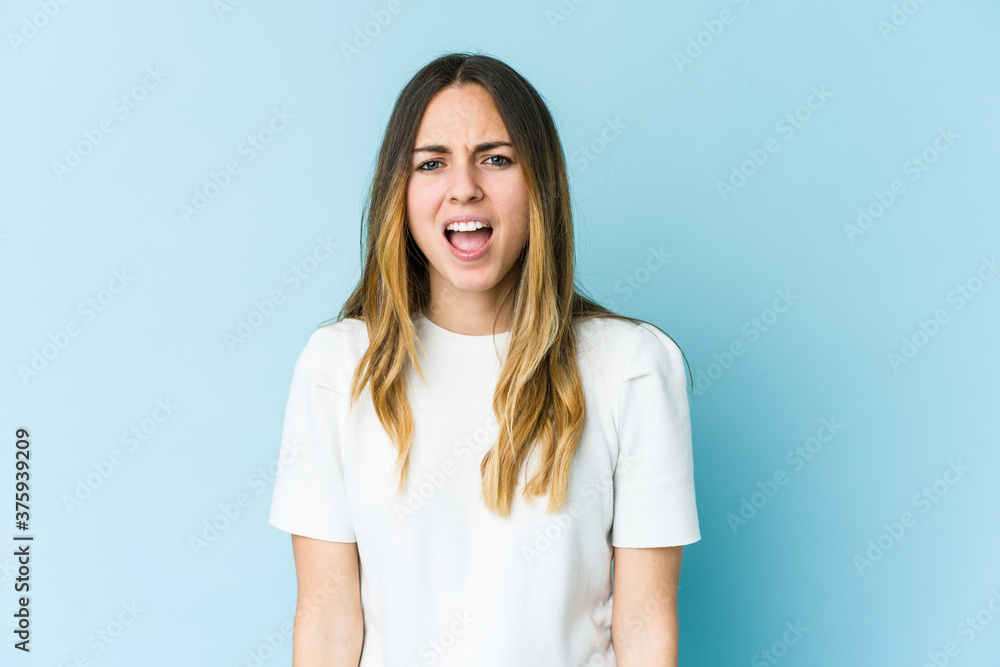 Young caucasian woman isolated on blue background shouting very angry, rage concept, frustrated. Young caucasian woman isolated on blue background shouting very angry, rage concept, frustrated.