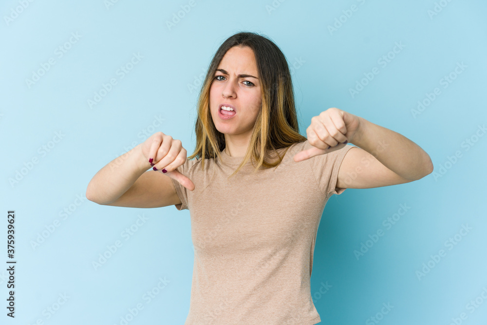 Fototapeta premium Young caucasian woman isolated on blue background showing thumb down and expressing dislike.