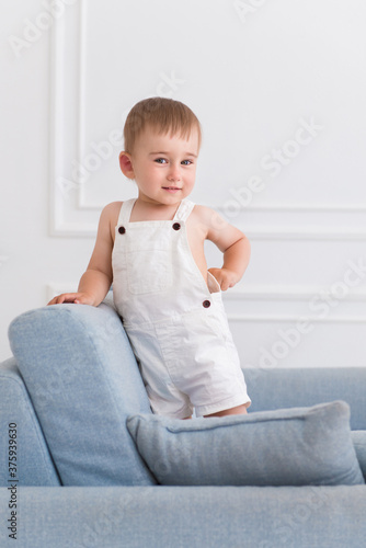 portrait of a little smiling boy child playing on the sofa in living room
