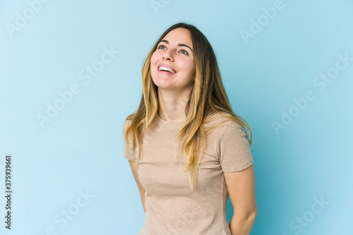 Young caucasian woman isolated on blue background relaxed and happy laughing, neck stretched showing teeth.