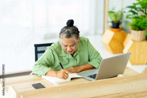 senior retirement Asian woman work from home with laptop computer in living room