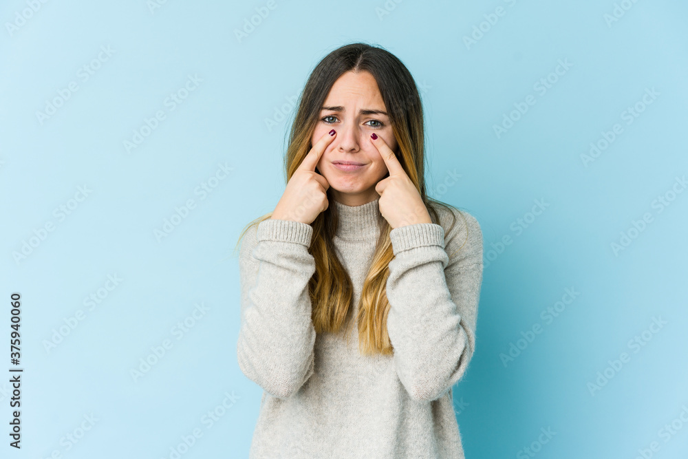 Young caucasian woman isolated on blue background crying, unhappy with something, agony and confusion concept.