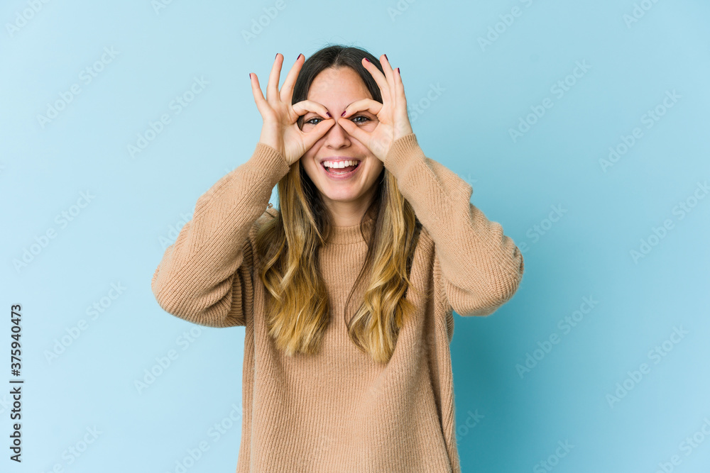 Young caucasian woman isolated on blue background excited keeping ok gesture on eye. Young caucasian woman isolated on blue background excited keeping ok gesture on eye.