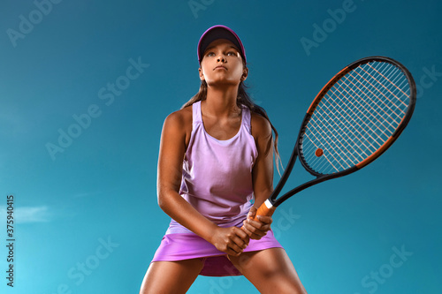 Tennis player. Beautiful girl teenager and athlete with racket in pink sporswear and hat on tennis court. Fashion and sport concept. photo