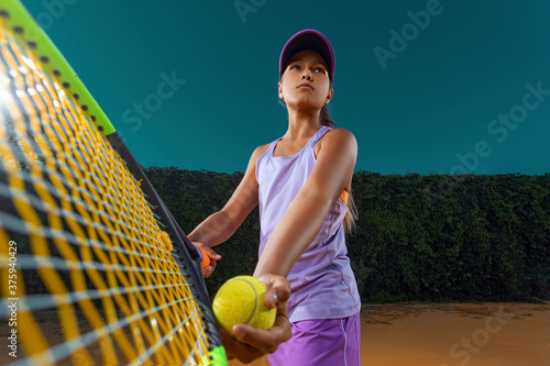 Tennis player. Beautiful girl teenager and athlete with racket in pink sporswear and hat on tennis court. Fashion and sport concept. © Mike Orlov